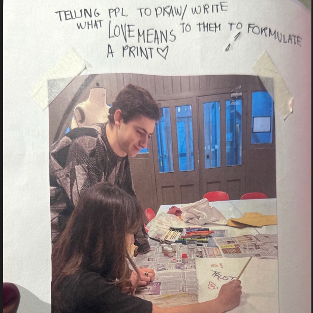 A handmade art journal page or scrapbook layout featuring a central photo of a young couple creating a print together, surrounded by handwritten notes and a piece of white denim fabric at the bottom.